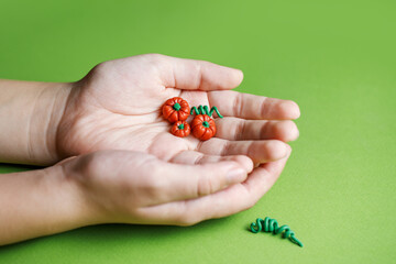 Decorative small pumpkin made of polymer clay in the hand of a child. Miniatures for playing in the dollhouse. Modeling from plasticine by children. Children's creativity. Horizontal photo.
