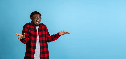 Flyer with young stylish african man wearing casual clothes isolated on navy studio background. Emotions, facial expression concept.