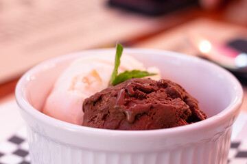 Chocolate and vanilla ice cream scoops on white bowl. Sweet dessert concept