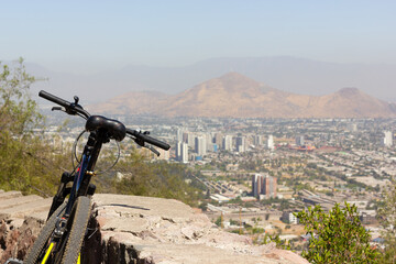 Mountain bike leaning on rock wall with Santiago city views on background on sunny day