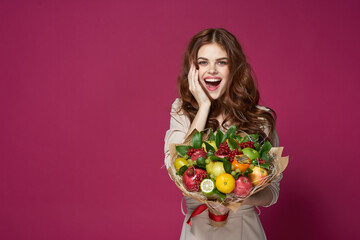 portrait of a woman fun posing fruit bouquet vitamins pink background