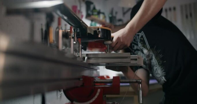 Luthier mounts the electric guitar on the jig at the musical instruments repairing shop, 4k 60p 10 bit