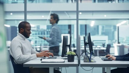 Modern Multi-Ethnic Office: Professional Black IT Engineer Working on Desktop Computer Opposite Caucasian Female Computer Science Specialist. Diverse Workplace with Corporate Feel but Creative Spirit