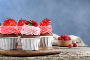 Sweet cupcakes with fresh berries on wooden table. Space for text