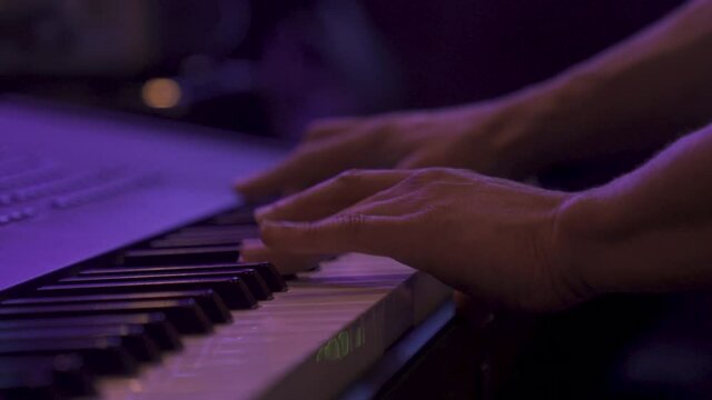 orbit shot of a man playing the keyboard in a venue handheld in 4k