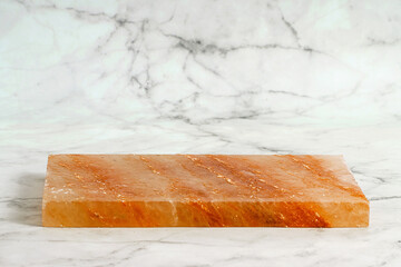 Pink himalayan salt block for cooking and serving the dish on marble background