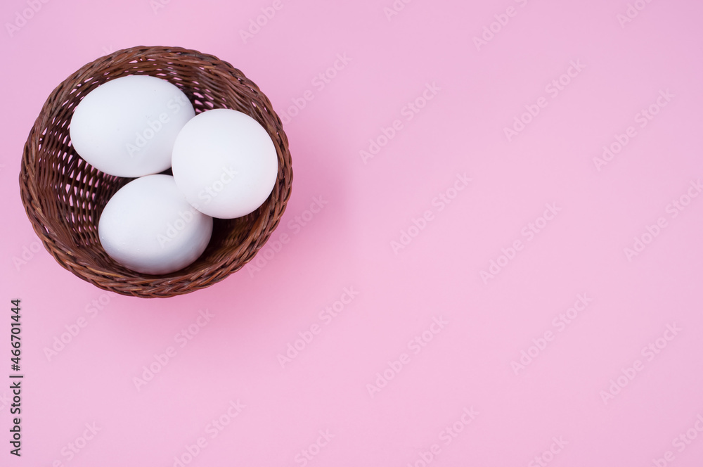 Poster isolated white eggs in a wicker canister on a pink background with copy space