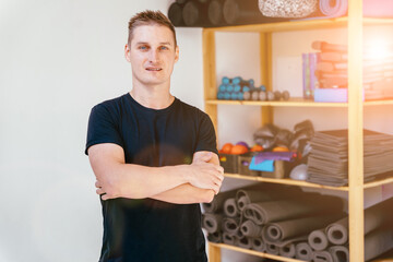 Handsome pilates male instructor in balck sportswear posing with shelves equipment, at the gym indoor. Balance Control Pilates Exercise.