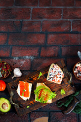 healthy sandwiches with smoked salmon avocado cucumber cream cheese on rye bread on dark background