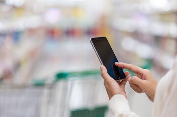 Hands woman using smartphone and shopping in a supermarket. Shopping concept