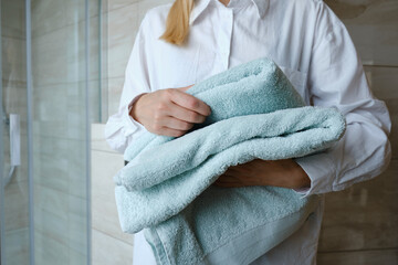 Close-up of bath towels in the hands of a girl. The woman takes towels and prepares for the body care procedure. Cleanliness concept. Spa treatments at home in a beauty salon or in hotels