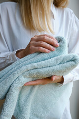 Close-up of bath towels in the hands of a girl. The woman takes towels and prepares for the body care procedure. Cleanliness concept. Spa treatments at home in a beauty salon or in hotels