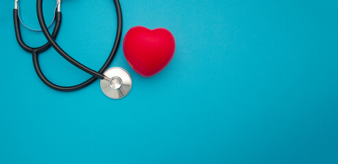 Top view of a stethoscope and a red heart shape on a blue background. Medical and healthcare concept