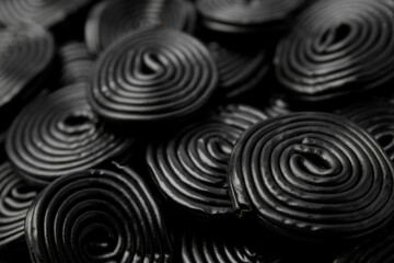 Tasty black liquorice candies as background, closeup