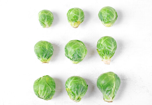 Brussels sprouts in three rows increasing in size on the white table. Beneficial effects of the vegetable on vision