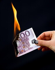 Five hundred Euros are burning with fire in hand isolated on black