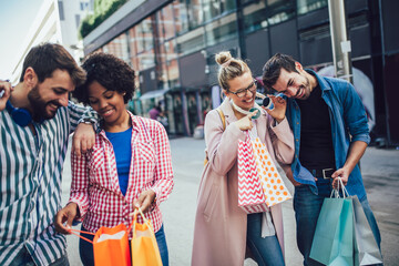 Group of friends walking along street with shopping bags and having fun.