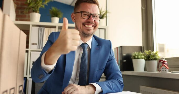 Businessman with glasses sitting at table and showing thumb up 4k movie