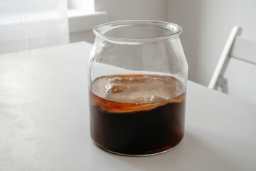Kombucha mushroom superfood probiotic beverage in glass on white interior background. Homemade fermented tea healthy for immunity and gut
