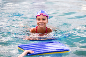 Fototapeta na wymiar Portrait of little smiling girl in swimming pool
