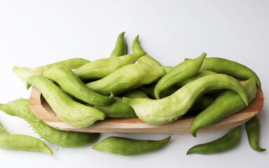 Cyclanthera pedata fruit from Cucurbitaceae family, unusual, rare healthy green tasty vegetable from the garden, climber gourd, isolated on a white background on a wooden tray.