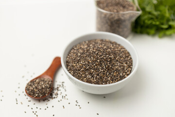 Chia seeds in wooden spoon and cup with space on white background