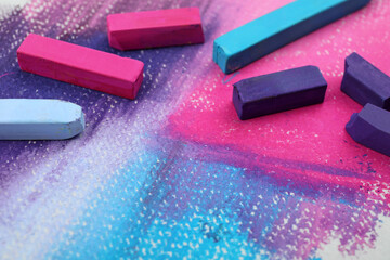 Colorful pastel chalks on abstract painting, closeup. Drawing materials