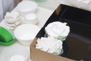 Homemade marshmallows are spread out on the table surface. Marshmallow in the form of roses. Close-up shot.