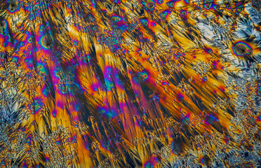 Extreme macro photograph of Vitamin C crystals forming abstract modern art patterns, when illuminated with polarized light, under a microscope objective with 10x magnification
