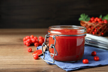 Delicious rowan jam in jar on wooden table. Space for text