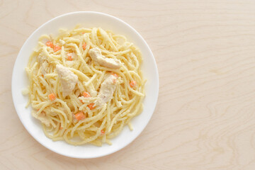 Cheesy chicken spaghetti with onion and carrot on a white plate.  Flat lay top view photo.  Food from above concept. 