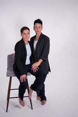 Obraz premium Two pretty women in business suits on a gray background. Girlfriends at the corporate party.