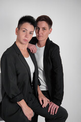 Two pretty women in business suits on a gray background. Girlfriends at the corporate party.