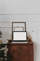 Blank screen laptop template with copy space. Home office desk table workspace. Modern nordic interior design decorated with Christmas tree.