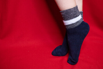 female legs in dark blue socks on a red background. place for text.