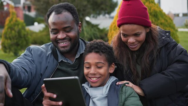 Positive African family making selfie on the tablet on terrace 