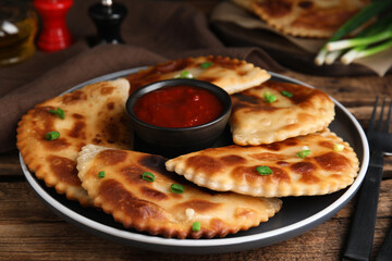 Delicious fried chebureki with ketchup served on wooden table