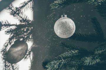 Glitter glass ball on Christmas tree making cosmic spotlight shadows on the wall in sun rays....