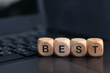 Wooden cube with the word BEST on laptop keyboard background
