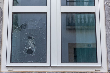 Cracked glass in a plastic vacuum window frame. A damaged window due to vandalism, natural disaster, or accident.