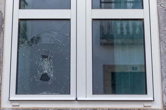 Cracked glass in a plastic vacuum window frame. A damaged window due to vandalism, natural disaster, or accident.