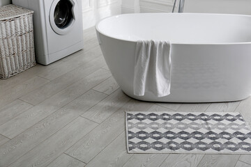 Stylish mat on floor near tub in bathroom. Interior design