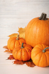 Fresh ripe pumpkins and dry leaves on white wooden table