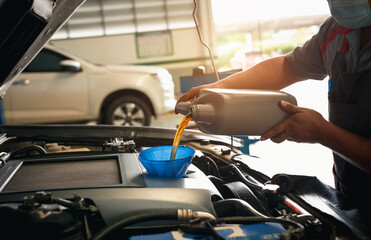 Car mechanic changing oil at repair shop or service center.