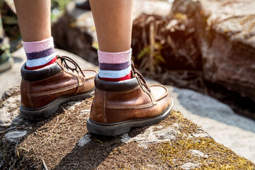 Hiking Hiking woman wearing trekking boots standing on the rock of mountain. Close up