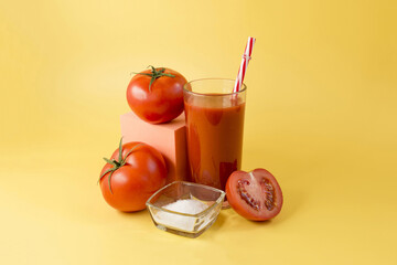 Natural tomato juice in a glass container with a decor of tomatoes, salt and an orange cube on an...