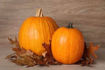 Fresh ripe pumpkins and dry leaves on wooden table