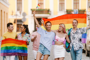 Multiracial men and women walking with rainbow flags during pride parade