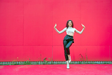 Happy dancing girl perform contemporary dance outside on red background, copy space. Female graceful dancer cool moving