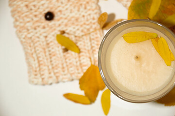 candle on the table warm sweater, fallen yellow leaves